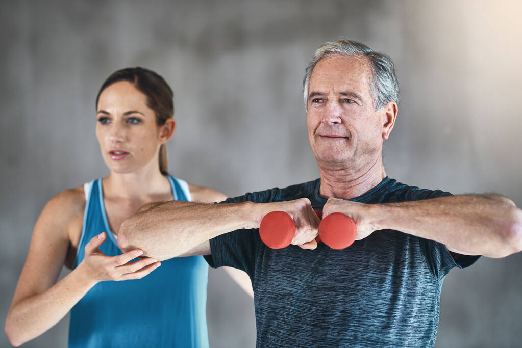Підтримка м'язової маси з регулярними вправами. старший чоловік використовує ваги за допомогою фізичного терапевта
 - Фото, зображення