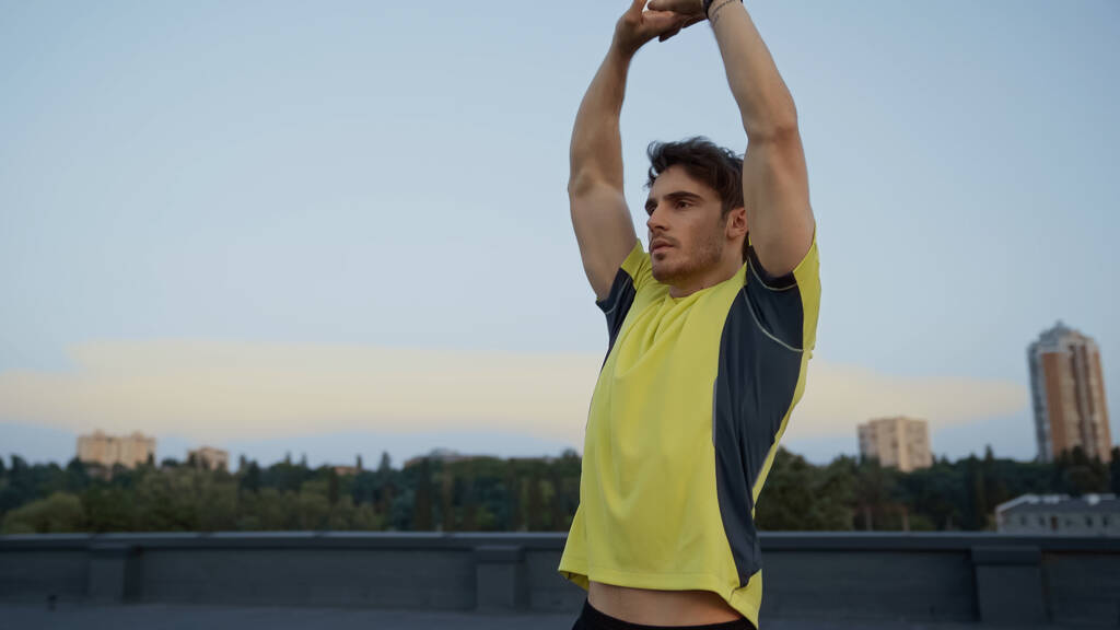 Young sportsman stretching on roof in evening  - Foto, Imagem