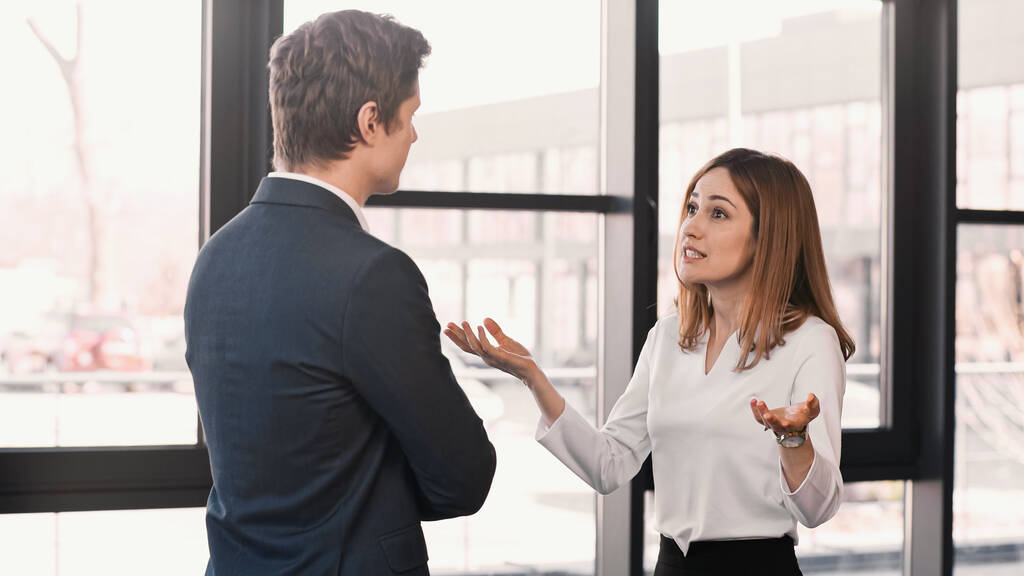 emotional woman gesturing during job interview with businessman in office - Photo, image