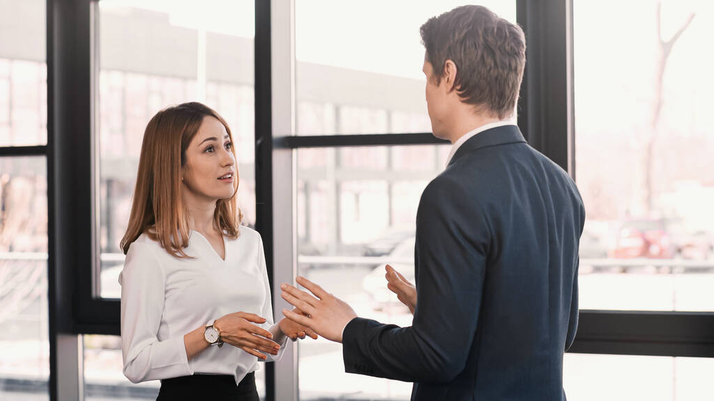businessman and smiling woman gesturing during conversation on job interview - Foto, immagini