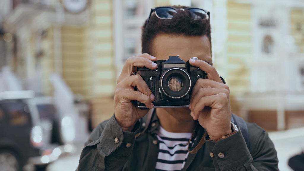 Bi-racial tourist taking photo on film camera outdoors  - 写真・画像