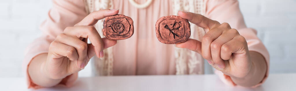 cropped view of fortune teller holding clay runes while predicting at home, banner - Foto, afbeelding
