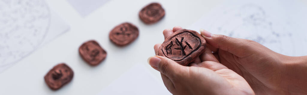 partial view of cropped fortune teller holing clay rune, banner - Foto, Imagen
