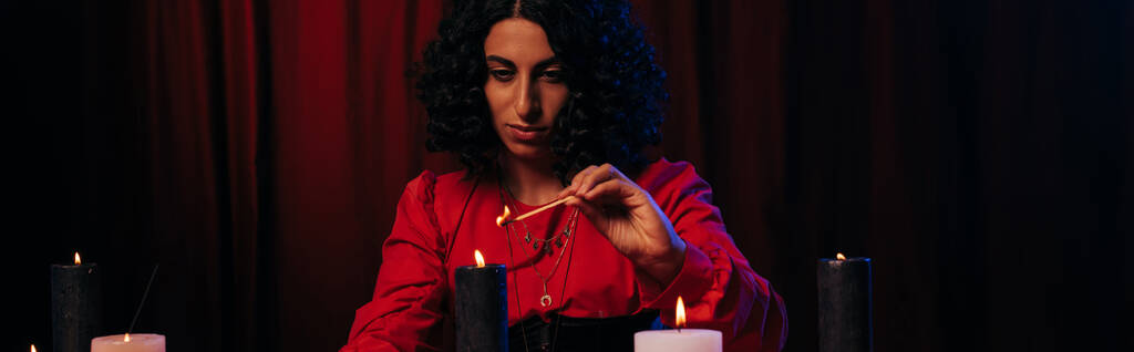 brunette medium lighting palo santo stick during spiritual session on dark background, banner - Foto, imagen