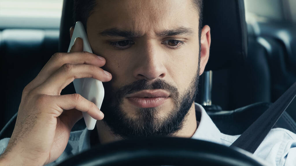 молодий і напружений чоловік говорить на мобільному телефоні в машині
 - Фото, зображення