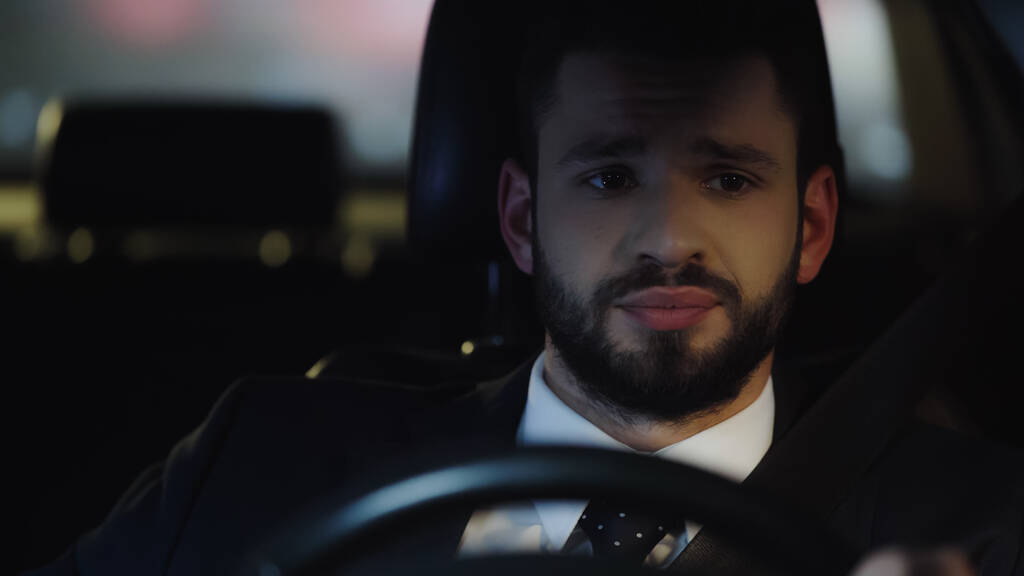 portrait of upset businessman driving automobile at night  - 写真・画像
