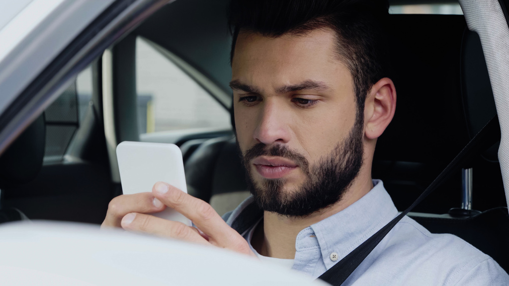 thoughtful man estimating route on smartphone while sitting in car - Фото, изображение