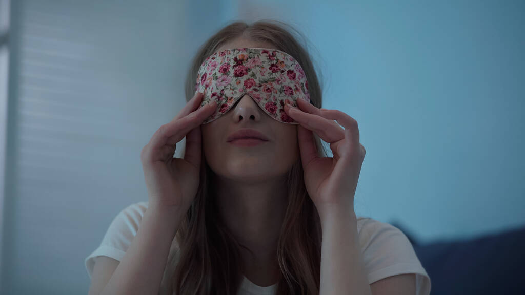Young woman wearing sleep mask at home at night  - Valokuva, kuva