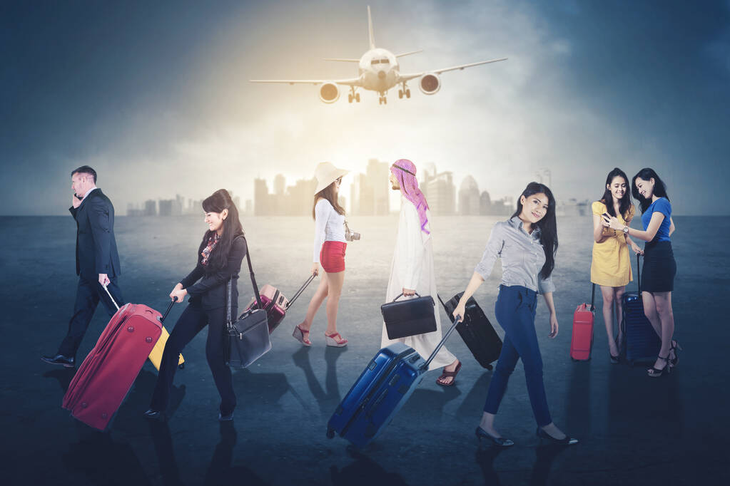 Täynnä ihmisiä, jotka kuljettavat matkatavaroita kävellessään lentokoneen taustalla - Valokuva, kuva