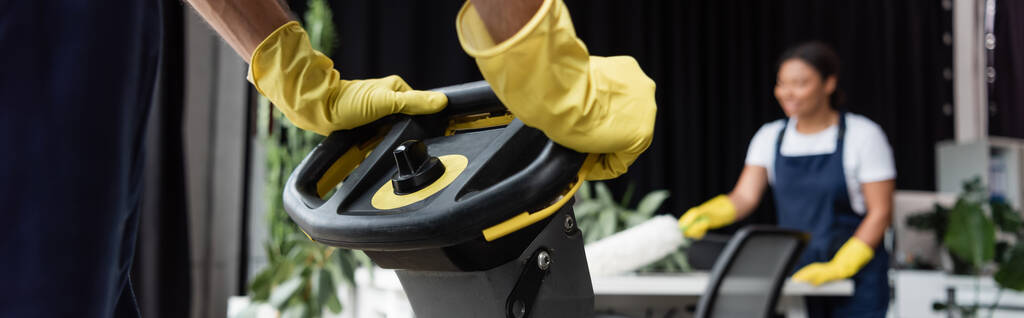 cropped view of man in rubber gloves near floor scrubber machine and bi-racial woman on blurred background, banner - Photo, Image