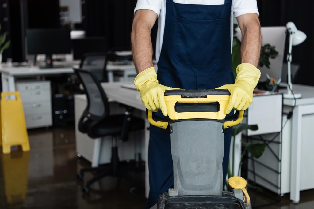 Ausgeschnittene Ansicht eines Mannes mit Bodenwaschmaschine bei der Arbeit im verschwommenen Büro - Foto, Bild