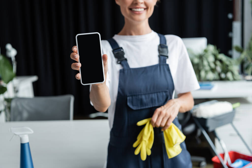 Teilbild einer fröhlichen Frau in Arbeitskleidung zeigt Smartphone mit leerem Bildschirm - Foto, Bild