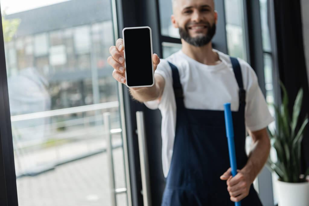 rozmazaný profesionální čistič zobrazující smartphone s prázdnou obrazovkou v kanceláři - Fotografie, Obrázek