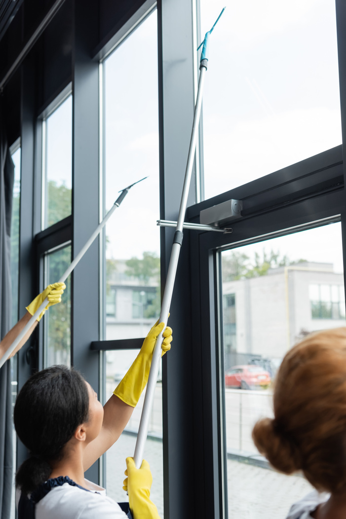 profesionální čističe v gumových rukavicích čištění velkých panoramatických oken v kanceláři - Fotografie, Obrázek