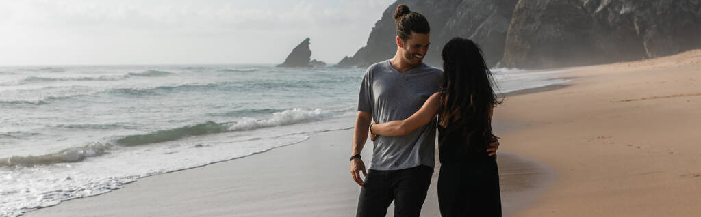 щасливий чоловік танцює з дівчиною в одязі на мокрій піску біля океану, банер
 - Фото, зображення