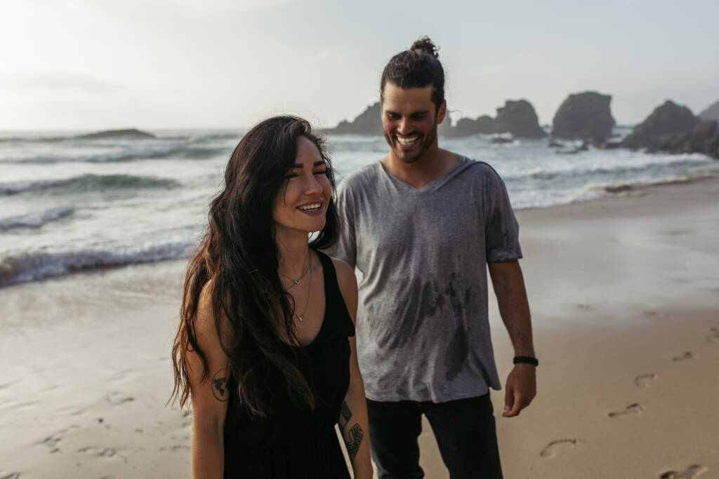 feliz y tatuada mujer sonriendo cerca alegre novio en la playa  - Foto, Imagen