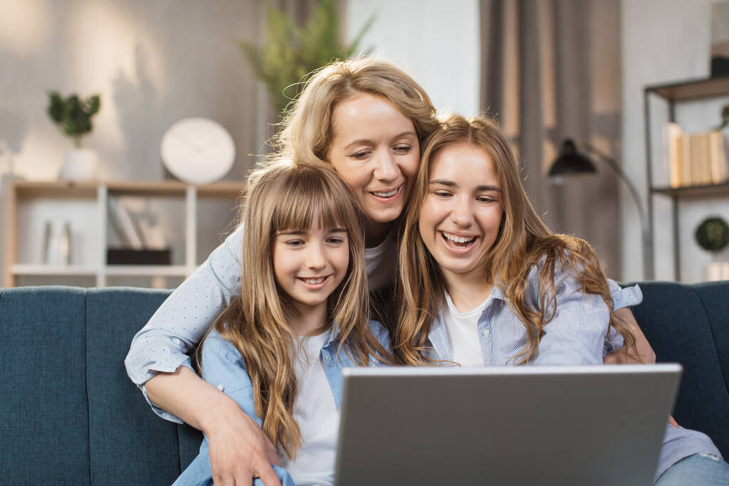 Single Caucasian mother and little children sitting on couch using laptop, family enjoy distant talk by video call, spend time in internet buying, e-commerce users, cartoons or video fun concept - Foto, afbeelding