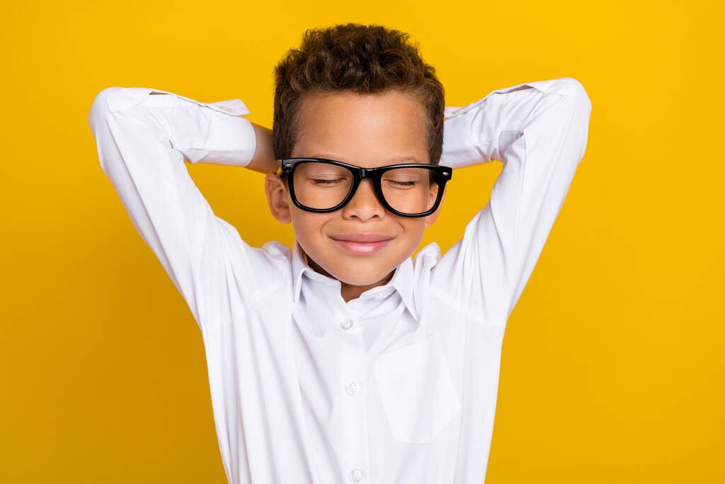 Portrait of cute dreamy boy stylish white clothes glasses hold hand behind head relax after school week isolated on yellow color background. - Foto, Imagen