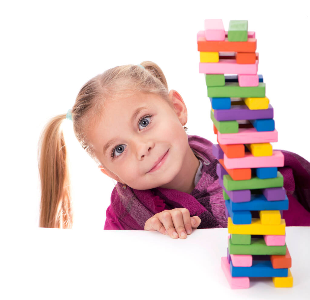 menina brincando com o jogo de madeira jenga no fundo branco
 - Foto, Imagem
