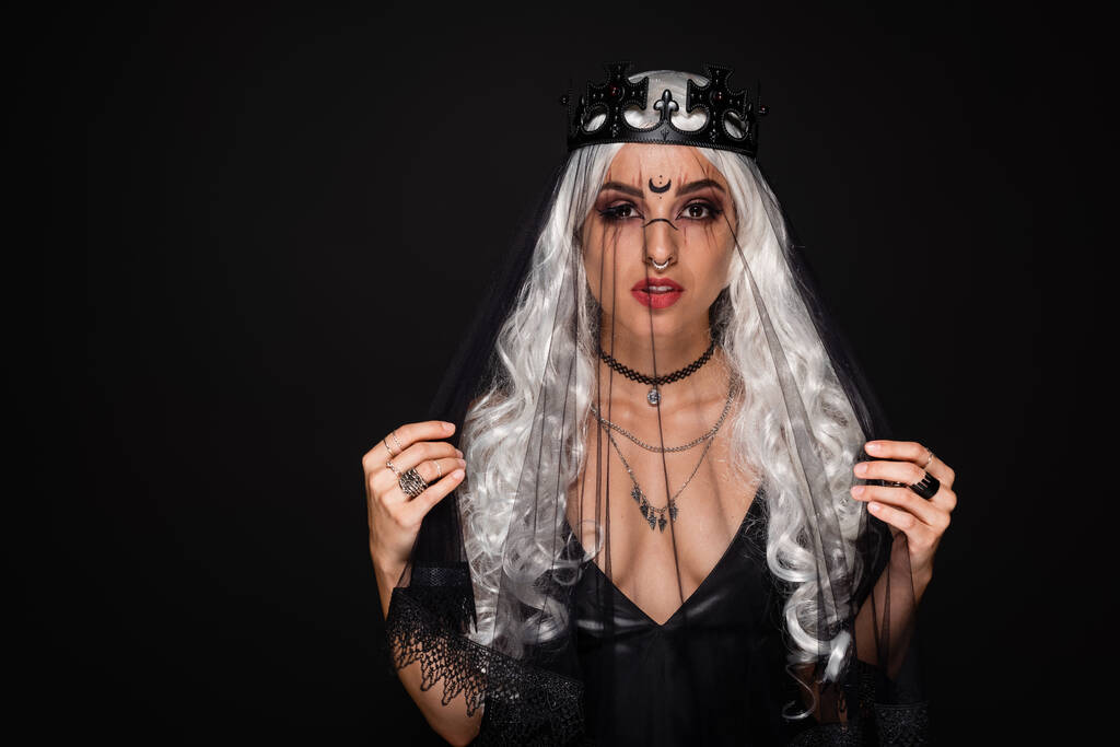 loira bruxa estilo mulher em coroa e véu olhando para a câmera isolada no preto - Foto, Imagem