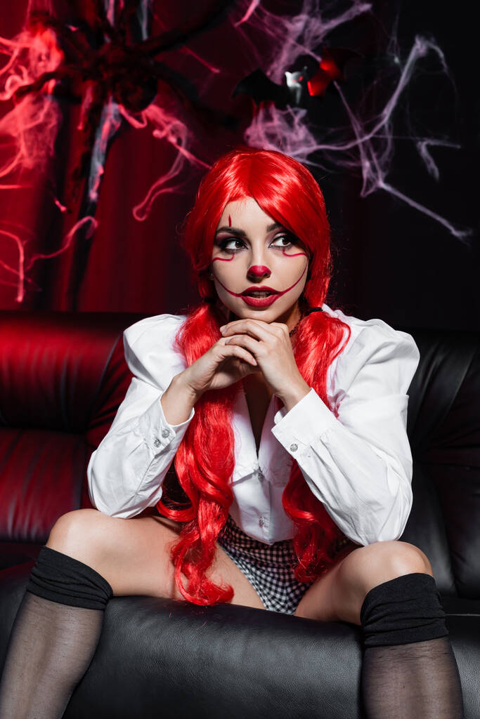 sexy rossa donna con Halloween trucco seduto su sfondo scuro vicino ragnatela - Foto, immagini
