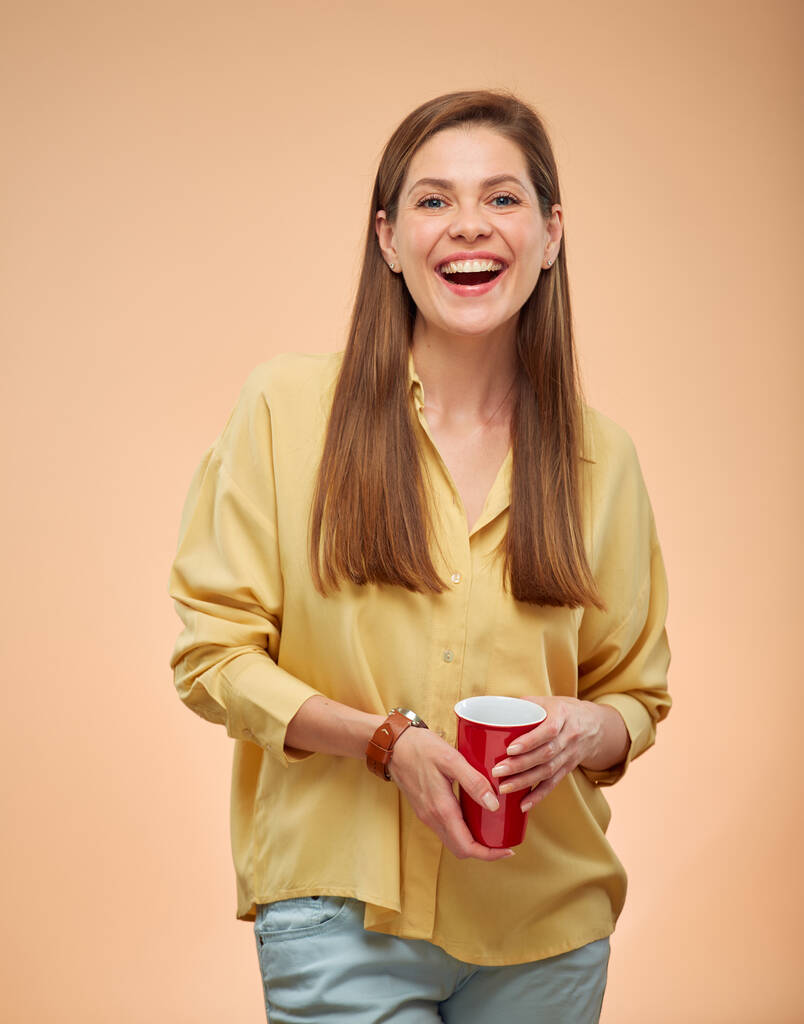 Onnellinen nainen eristetty muotokuva keltaisella pohjalla. Nuori nainen pitkät hiukset tilalla punainen kahvi kuppi. - Valokuva, kuva