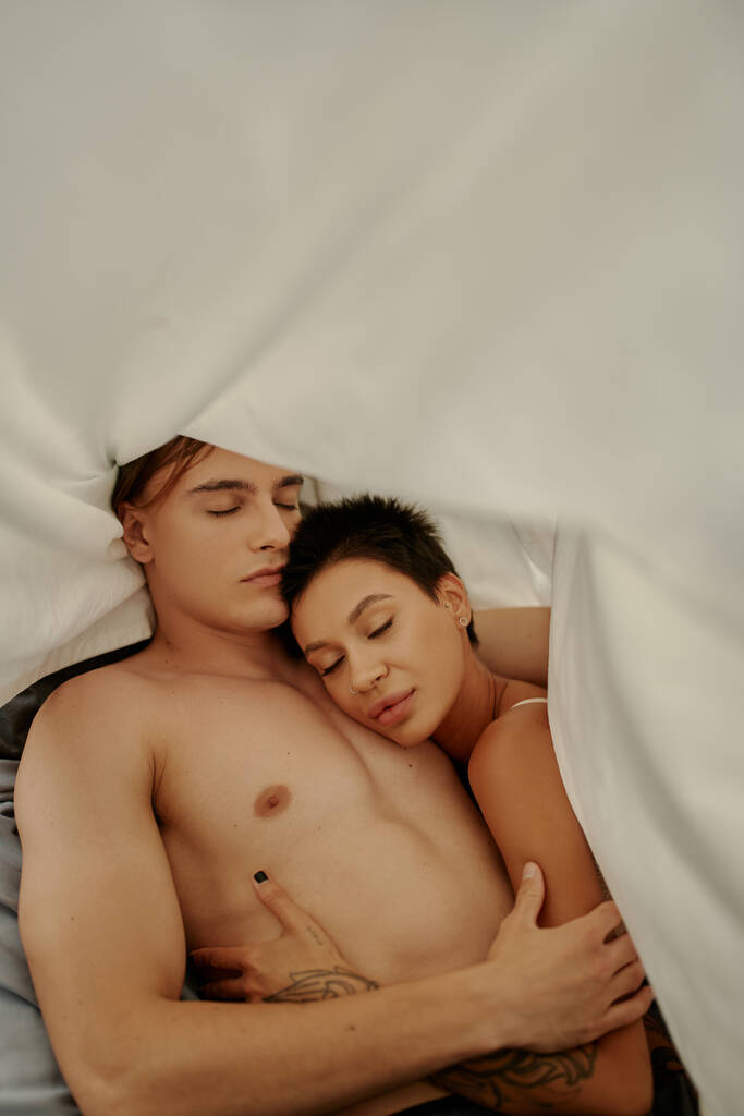 Top kilátás izmos férfi ölelés tetovált barátnő takaró alatt otthon - Fotó, kép