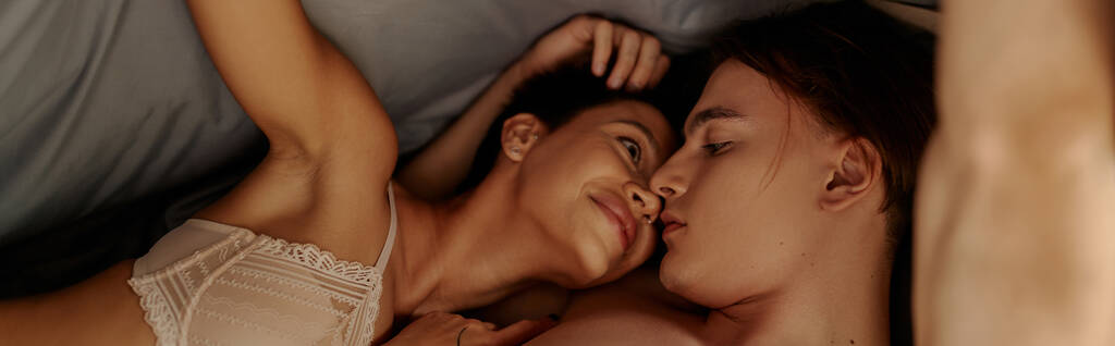 Vášnivý muž líbání mladé přítelkyně v podprsenka pod postelí, banner  - Fotografie, Obrázek