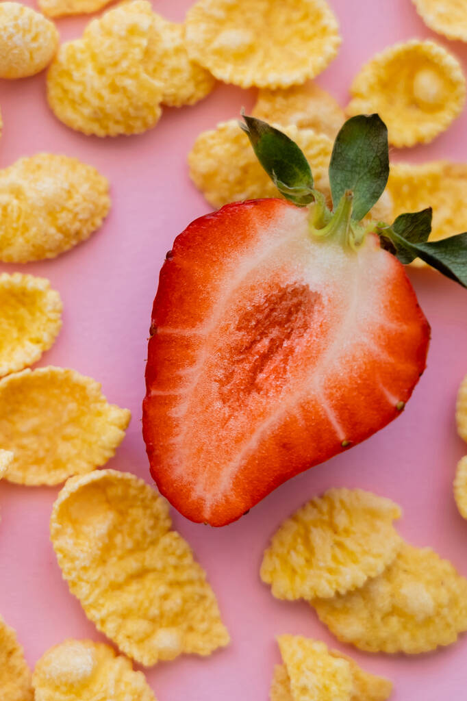 puolet tuoretta viipaloitu mansikka ympärillä rapea maissi hiutaleet vaaleanpunainen - Valokuva, kuva