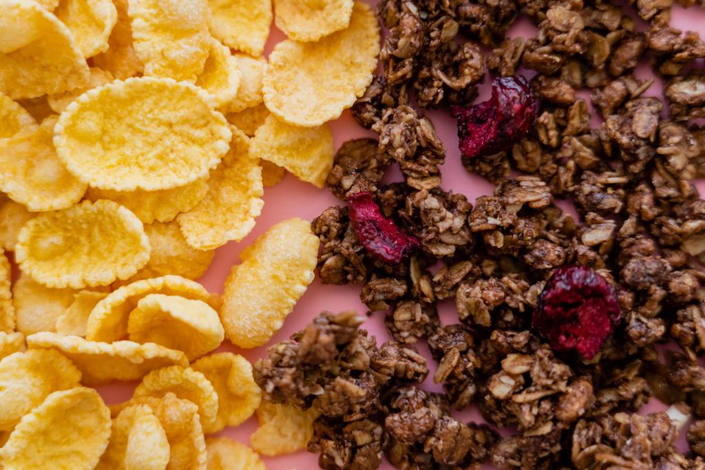 vista de perto de flocos de milho crocante e granola crocante em rosa  - Foto, Imagem