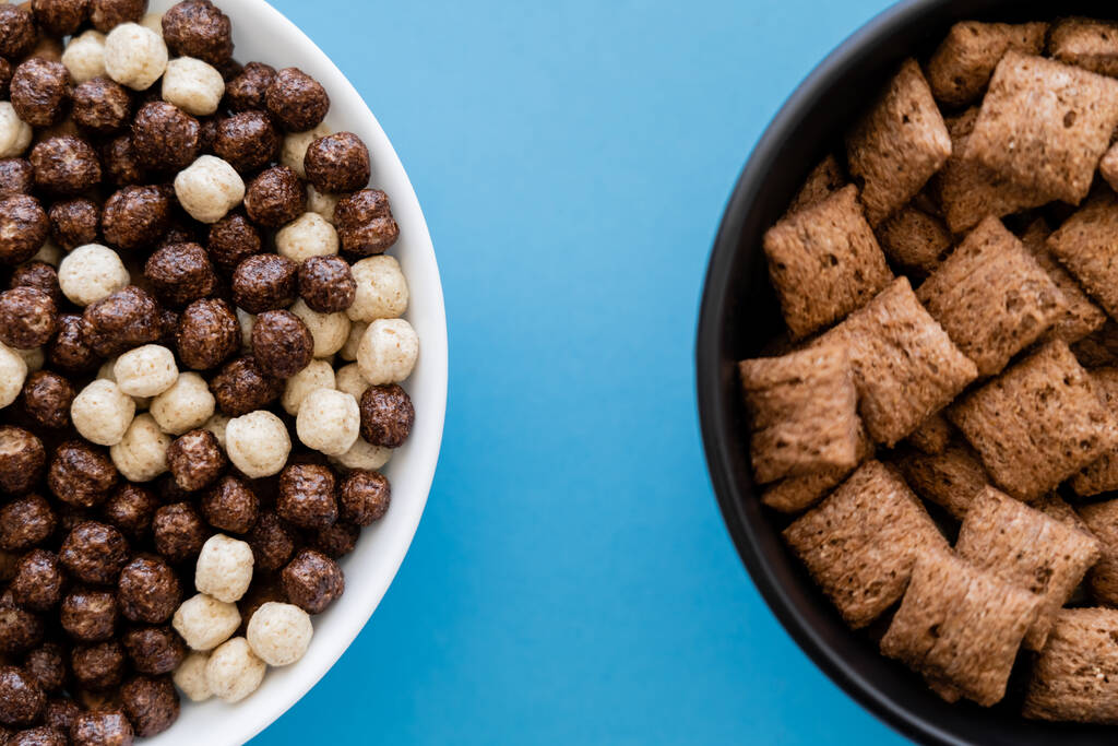 top view of bowls with tasty cereal balls and puffs isolated on blue - Photo, Image