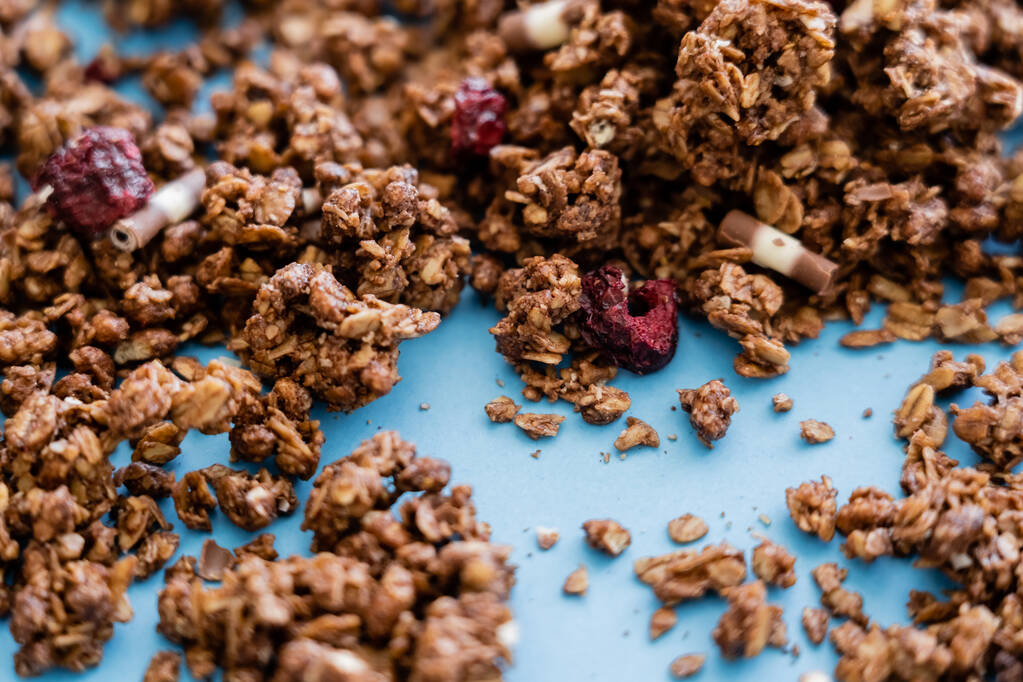 close up of crunchy granola with dry berry on blue background  - Photo, Image
