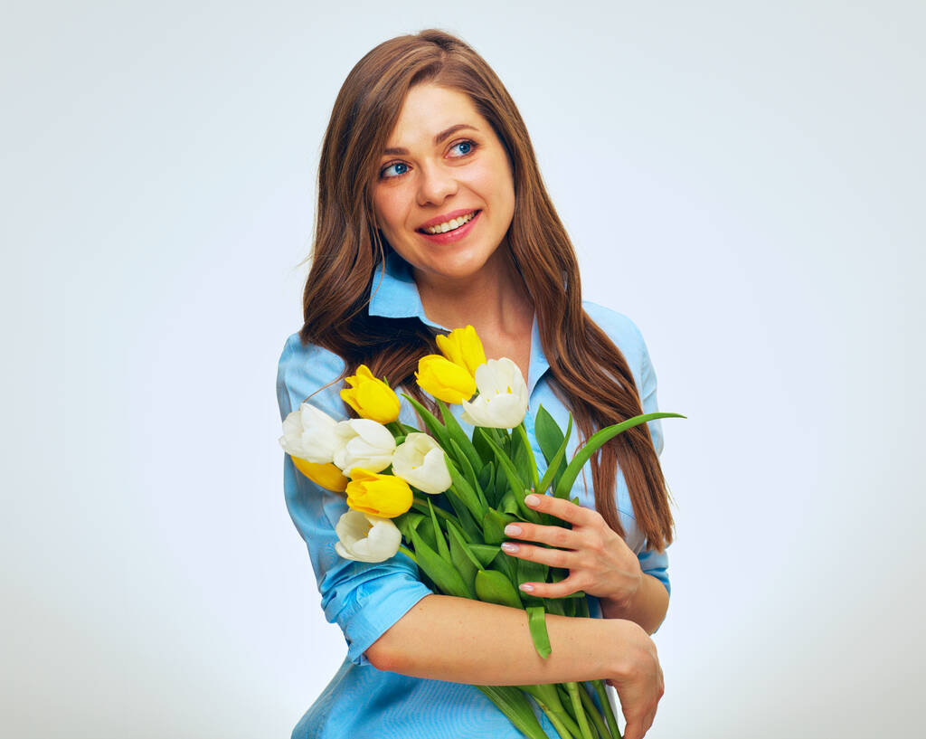 Χαμογελώντας ευτυχισμένη γυναίκα κρατώντας λουλούδια και κοιτάζοντας αλλού. απομονωμένη γυναίκα προσωπογραφία. - Φωτογραφία, εικόνα