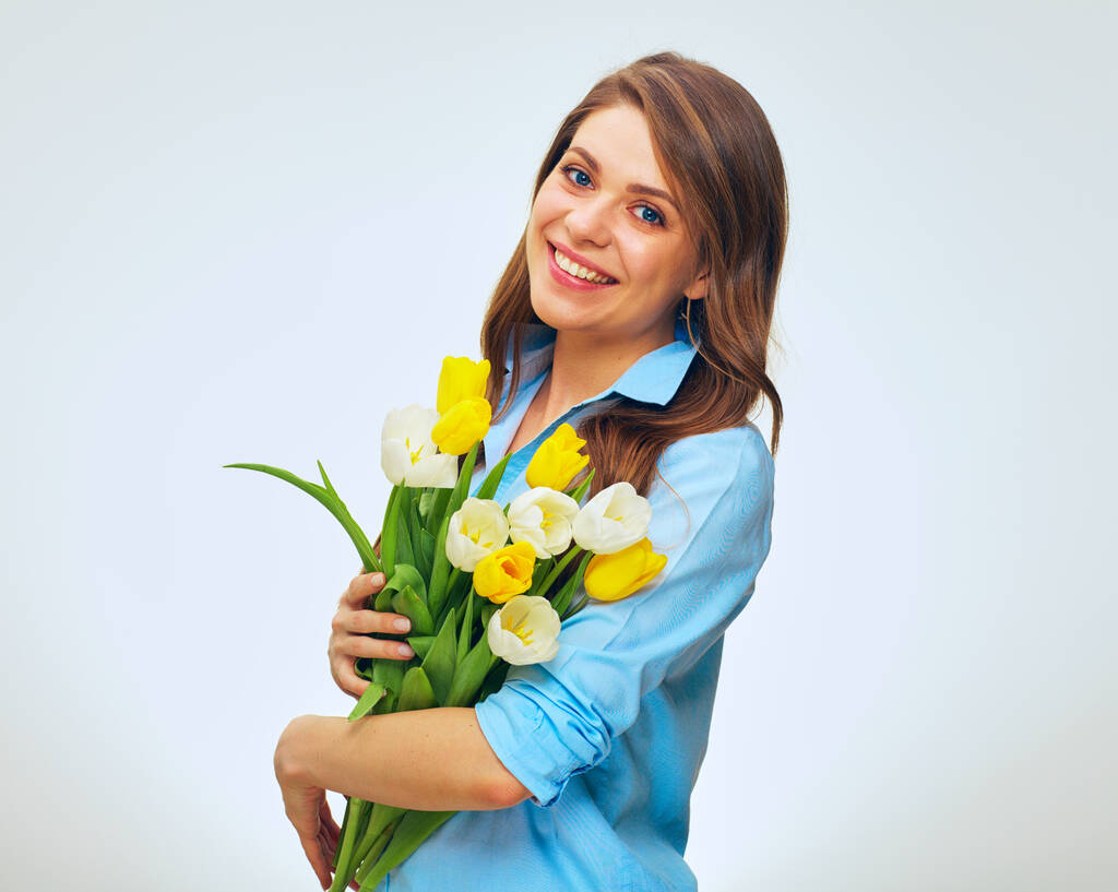 Glückliche Frau mit gelben und weißen Tulpen in der Hand. isoliertes Frauenporträt in blauem Hemd. - Foto, Bild