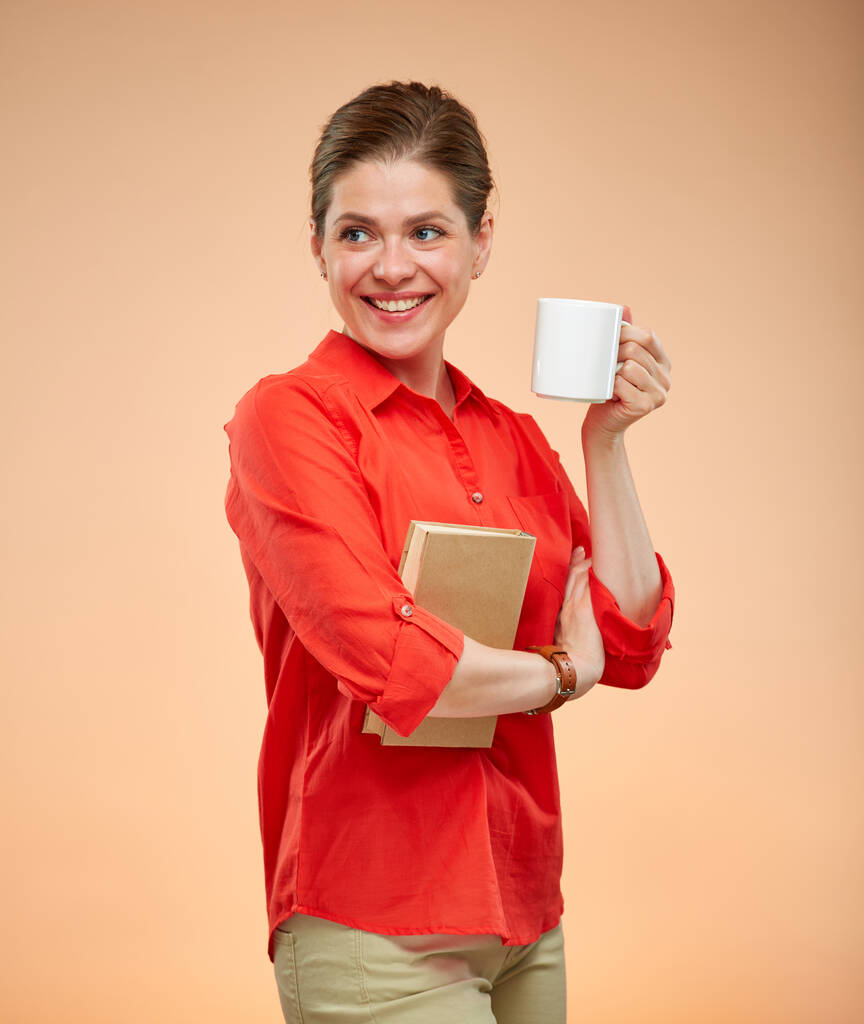 Professeur souriant ou étudiante en chemise rouge tenant le livre et la tasse blanche. Portrait isolé. - Photo, image