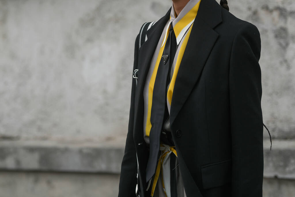 Milánó, Olaszország - február 24.: Utcai stílus, sárga és szürke ing, fekete Prada nyakkendő, fekete kabát, fehér Prada táska. - Fotó, kép