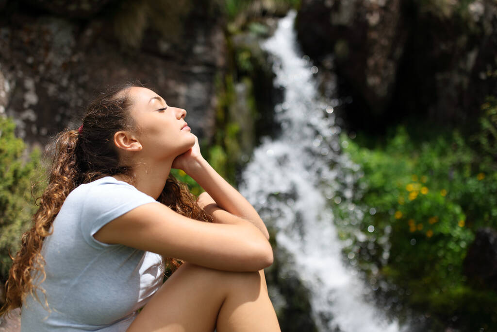 Sivukuva muotokuva naisen rentouttava pieni vesiputous vuorella - Valokuva, kuva