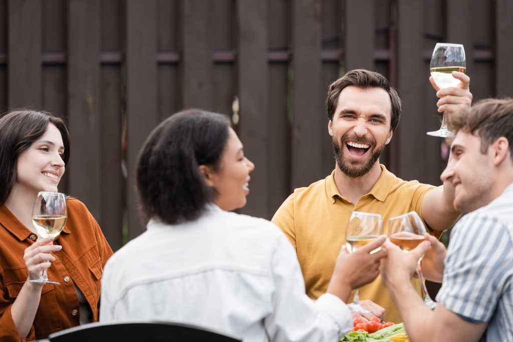 Innoissaan mies tilalla viiniä lähellä rotujenvälinen ystäviä aikana bbq osapuoli ulkona  - Valokuva, kuva