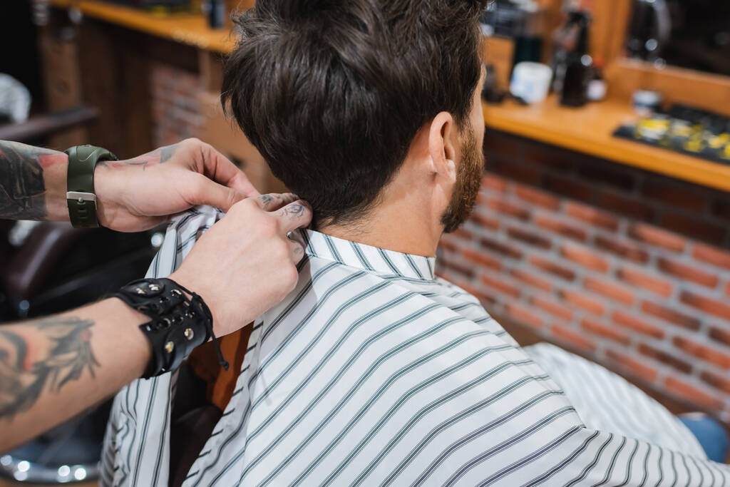 tatuado barbeiro colocando cabeleireiro capa no morena homem - Foto, Imagem