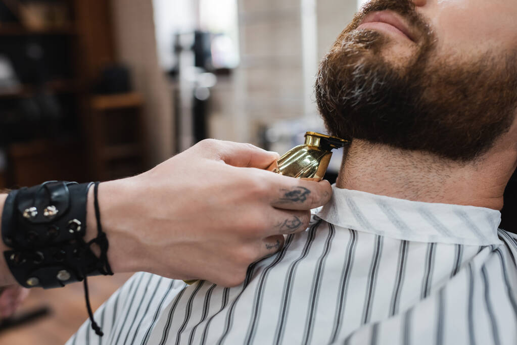 partial view of barber trimming neck of bearded man with hair clipper in barbershop - Photo, Image