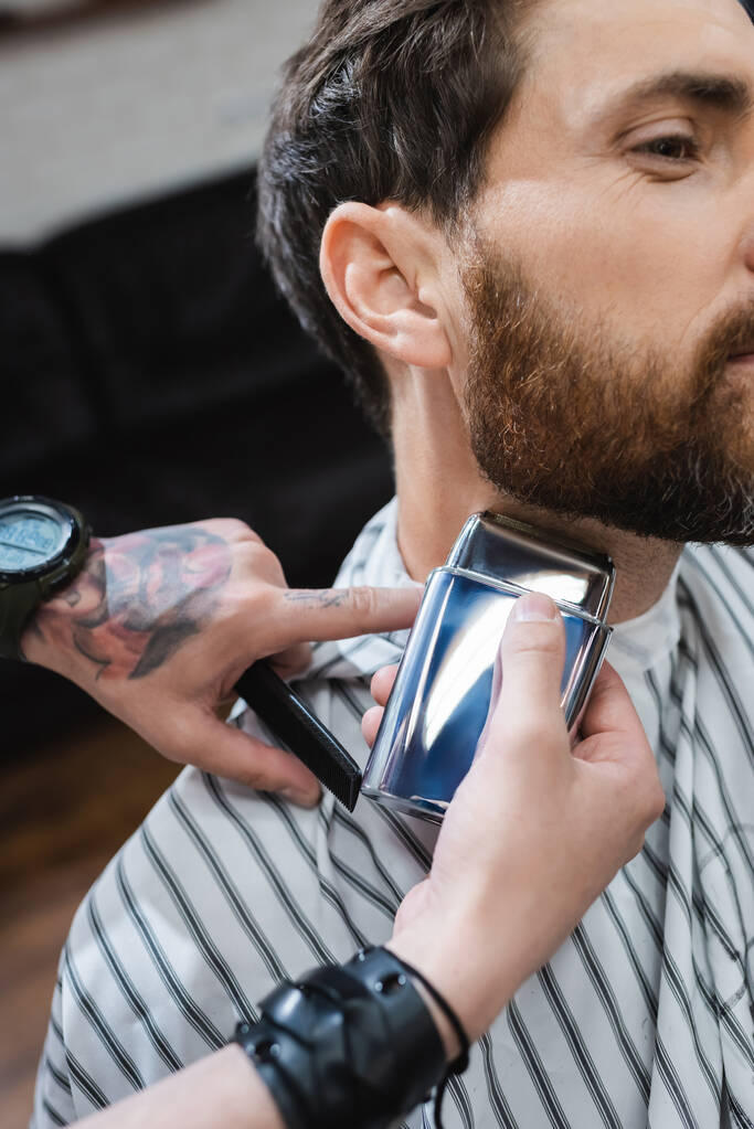 vista recortada de peluquero afeitado cuello de hombre barbudo con afeitadora eléctrica - Foto, Imagen