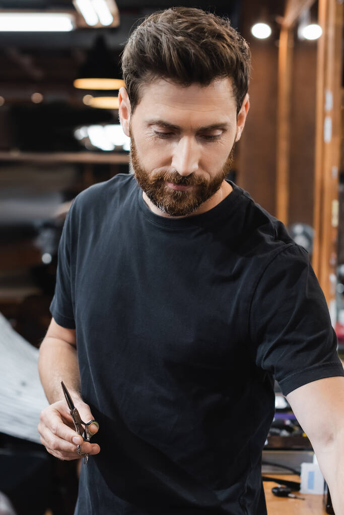 бородата брюнетка перукар тримає ножиці в салоні краси
 - Фото, зображення