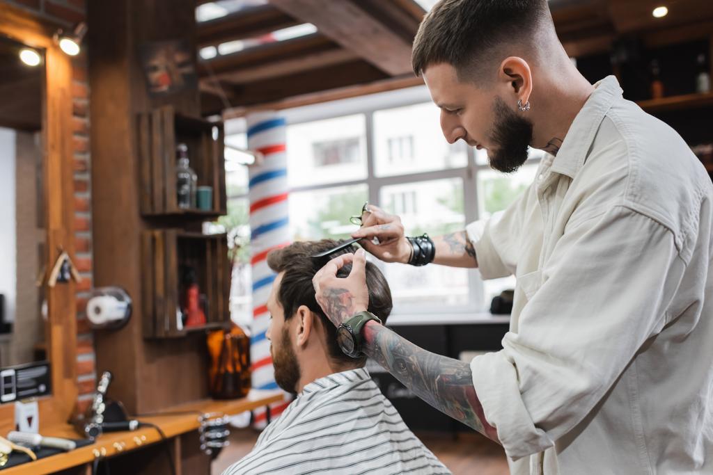 Bearded barber cutting hair of man in barbershop  - Photo, Image