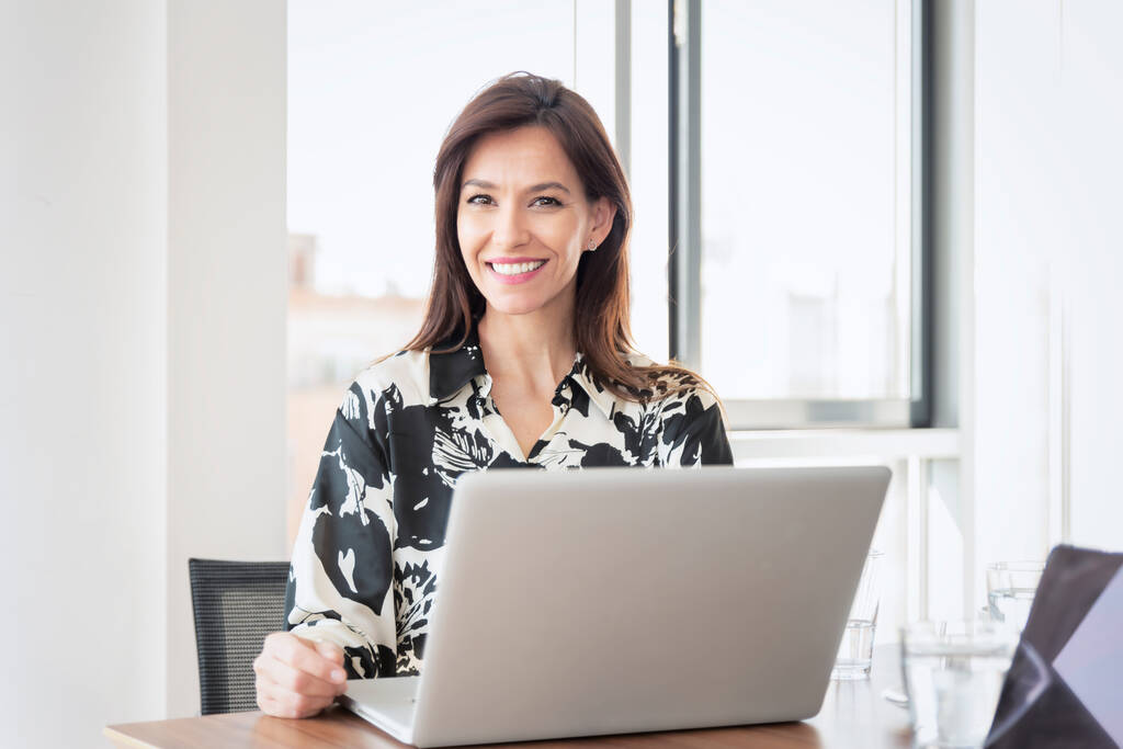 Gros plan d'une femme d'affaires d'âge moyen assise au bureau et travaillant sur un ordinateur portable dans un bureau moderne. - Photo, image