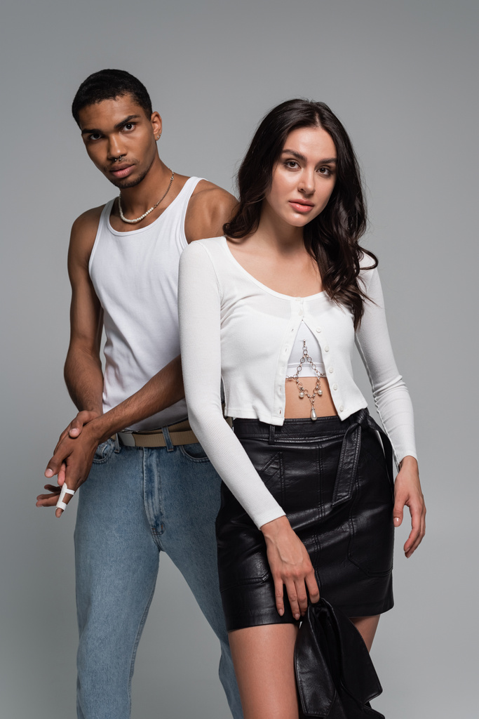 young african american man in tank top and pretty woman in leather skirt posing isolated on grey - Photo, Image