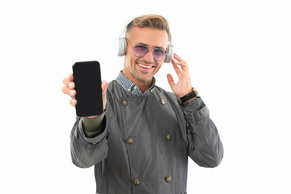 Happy guy in headphones showing smartphone. Listening to music with smartphone. Mobile music. Smartphone and music. - Fotoğraf, Görsel