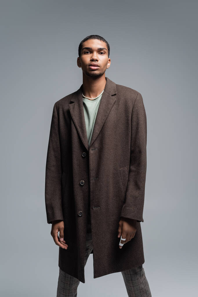 young african american man in woolen coat looking at camera isolated on grey  - Photo, Image