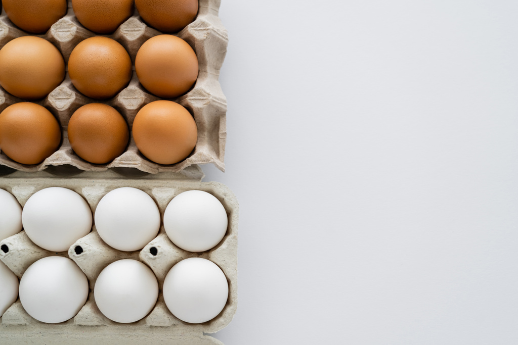 Vista dall'alto di uova naturali in contenitori su sfondo bianco  - Foto, immagini
