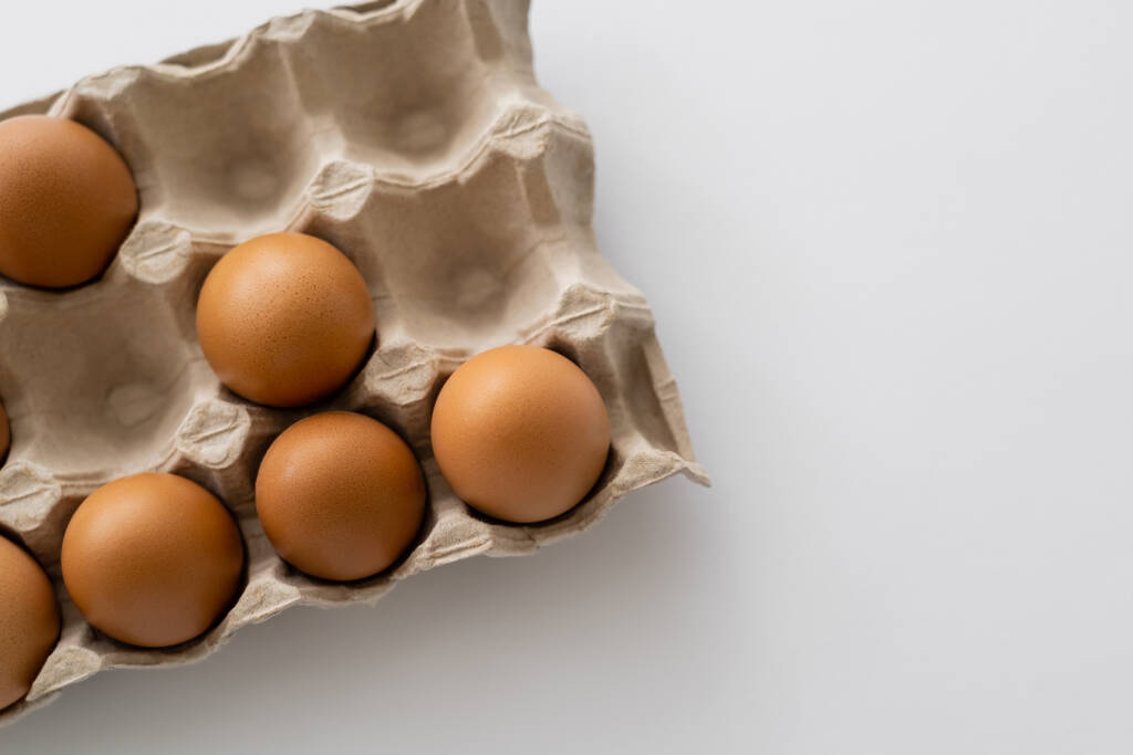 Draufsicht auf Bio-braune Eier im Container auf weißem Hintergrund  - Foto, Bild