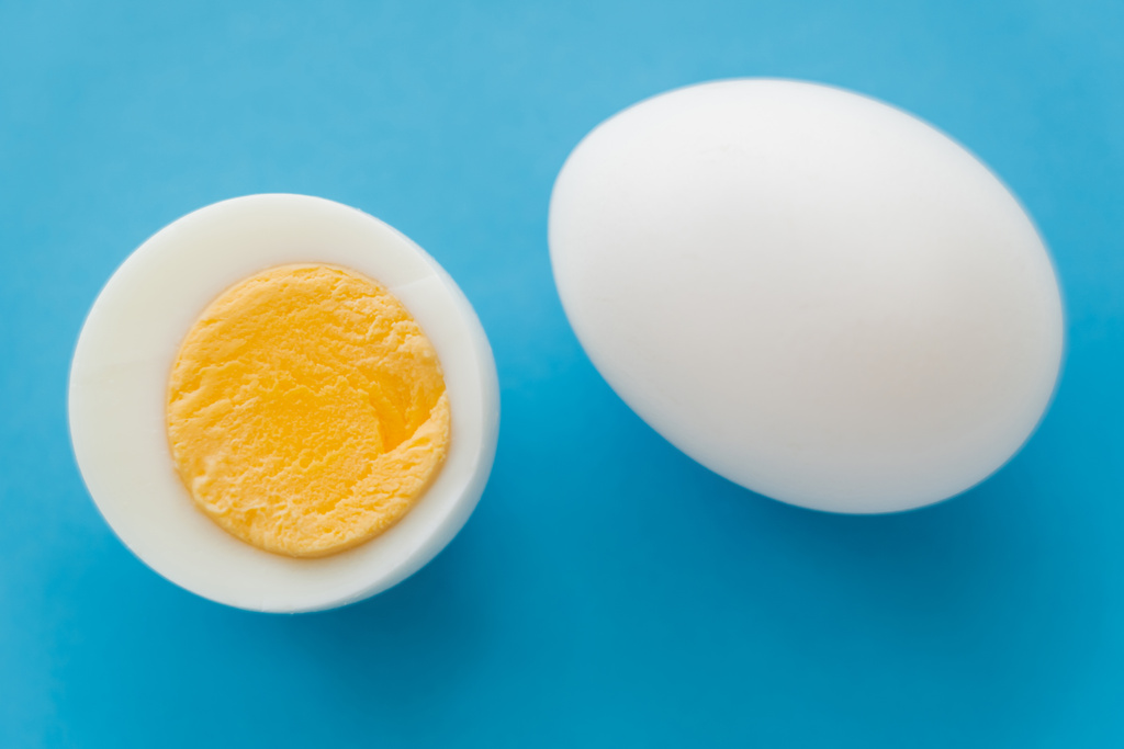 Widok z góry naturalne gotowane jajko z żółtkiem na niebieskim tle - Zdjęcie, obraz